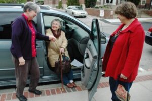 Volunteer Driver assist her passenger getting out of the car.